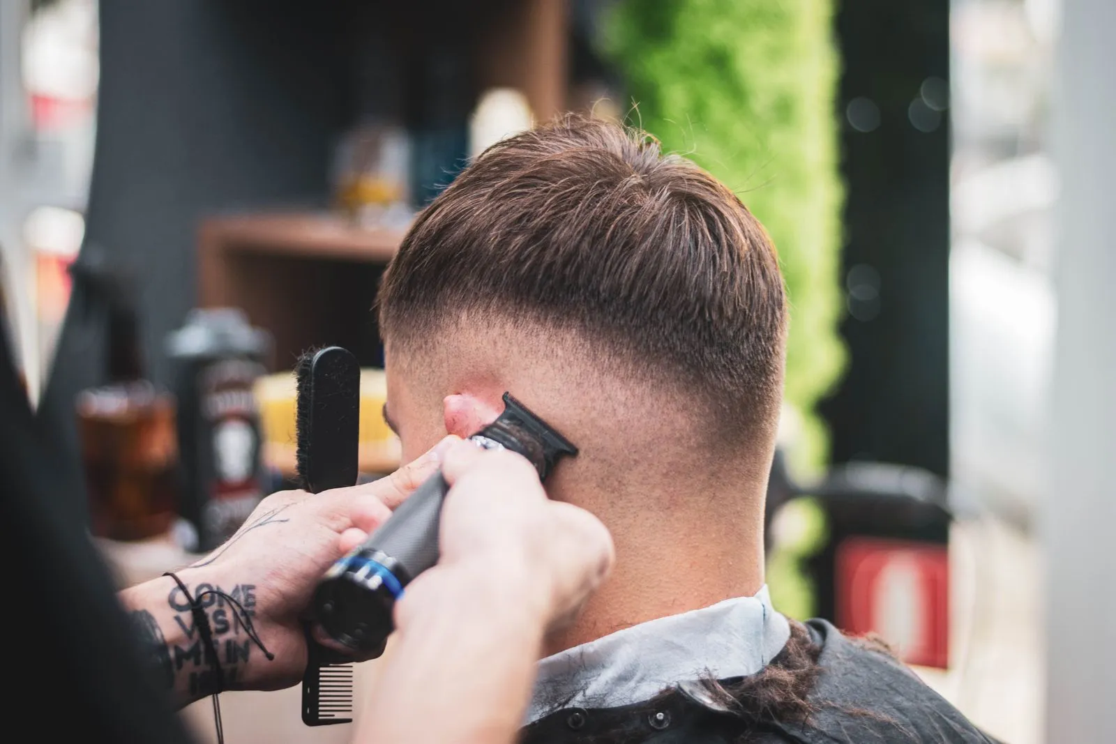 A barber skillfully trims a young man's hair in a modern salon setting, showcasing expertise and precision.